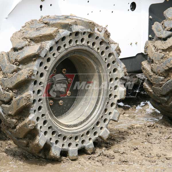 Heavy-duty McLaren solid cushion skid steer tire covered in mud with deep, aggressive tread