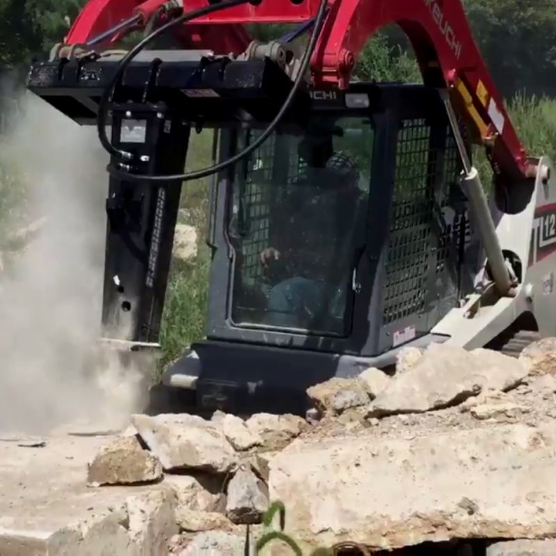 skid steer in action with the blue diamond hydraulic breaker attachment