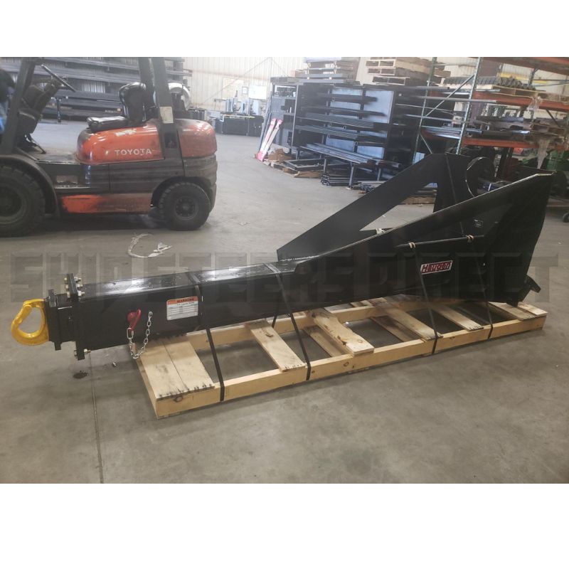 Black telehandler boom attachment secured on a wooden pallet inside a warehouse