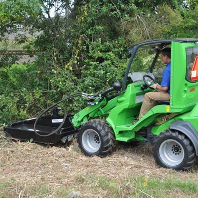 driving a mini skid steer with the blue diamond brush cutter in the bushes