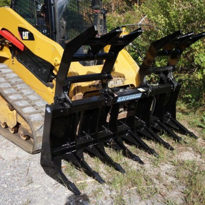 front view of blue diamonds severe duty rake grapple fully open and attached to CAT skid steer