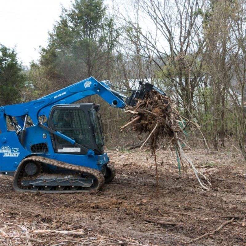 Blue diamonds Severe Duty Rake Grapple attached to skid steer carrying a load of brush