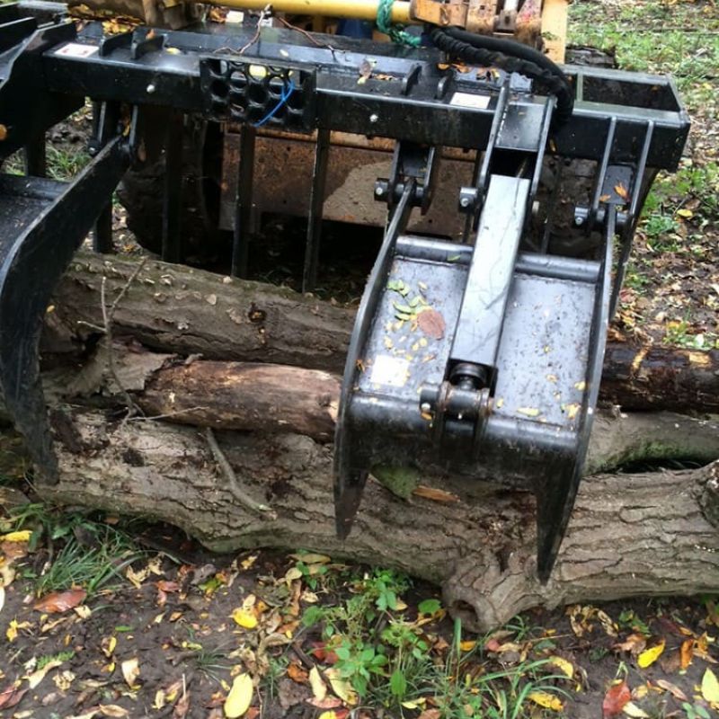 Front view of Blue diamonds Severe Duty Root grapple being used to lift logs