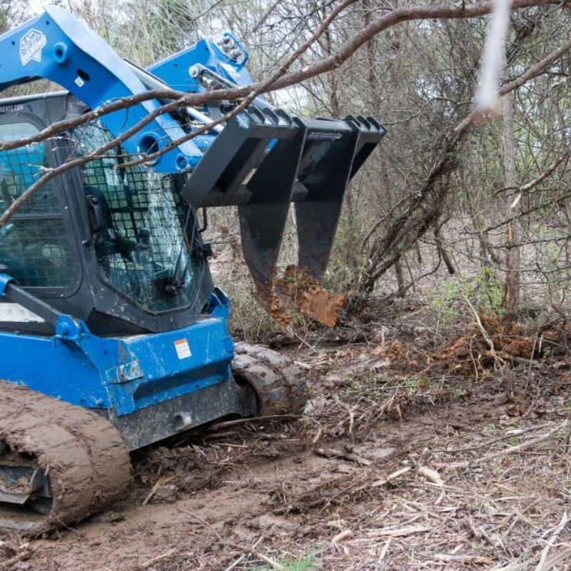 skid steer in action with the blue diamond tree grubber