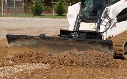 Bobcat skid steer with the dirt dozer blade attachment in action