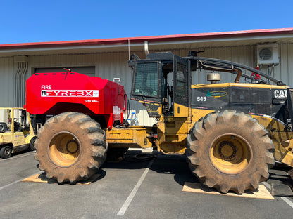Large CAT forestry machine fitted with a red FYREBX fire attachment parked outside a shop on a sunny day