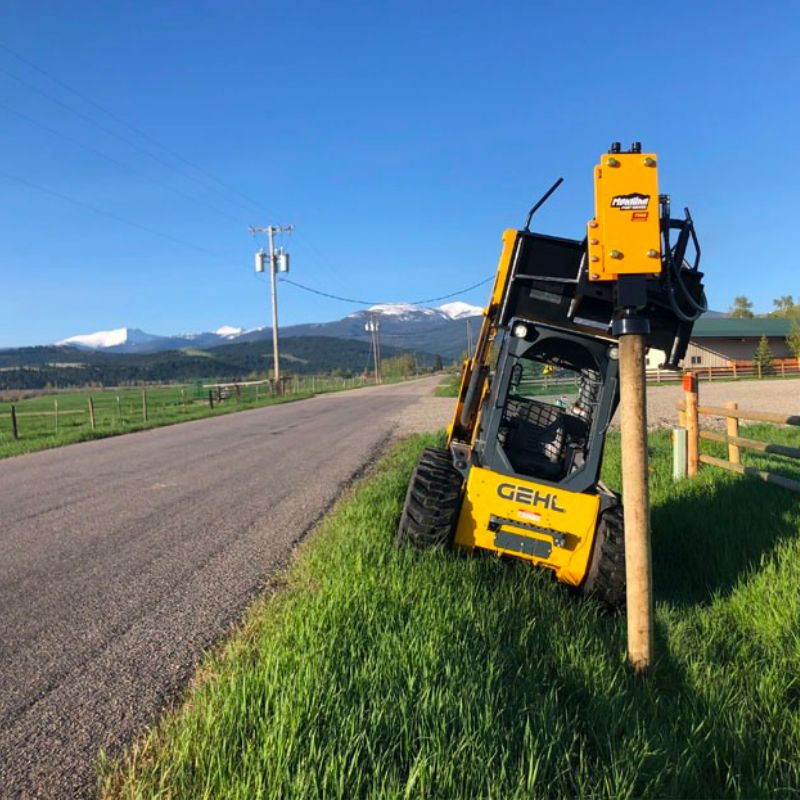 Montana post driver on a Gehl skid steer next to a highway