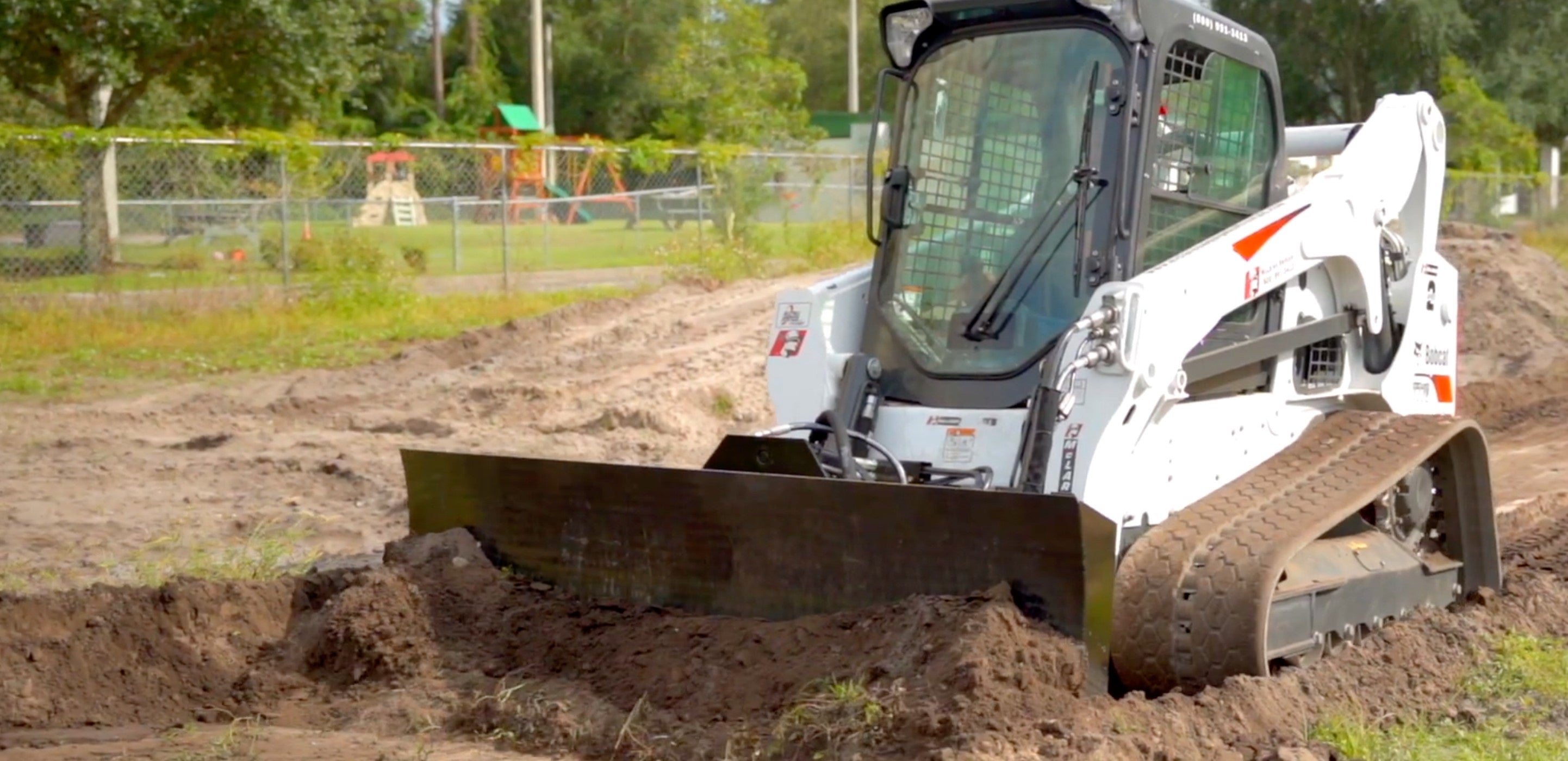 Moving dirt with the dirt dozer blade attachment by Mclaren on a bobcat skid steer