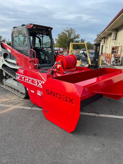 Red FYREBX SNOBX snow and debris attachment mounted on a track loader parked outside a shop