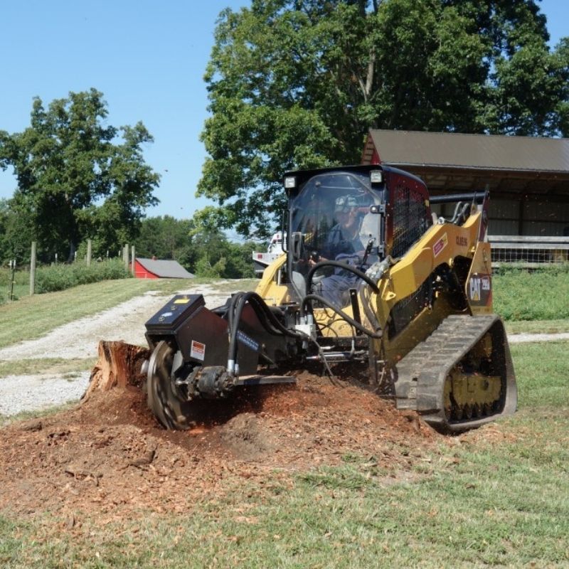 Skid steer with the Blue Diamond stump grinder attachment in action