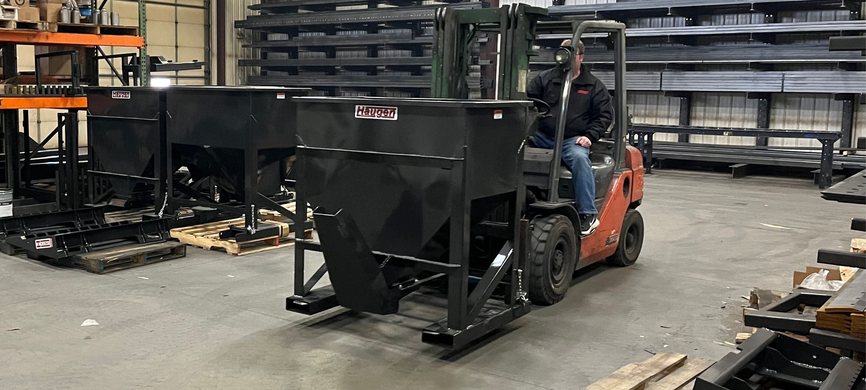 Man driving a skid steer with the Haugen concrete hopper attachment. 