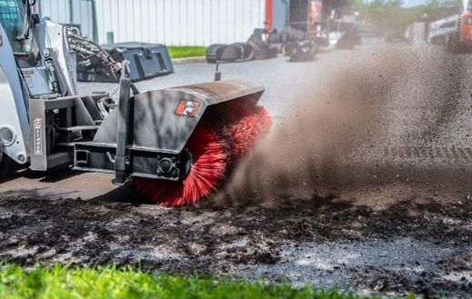 Cleaning the ground with the McLaren angle broom attachment on a skid steer