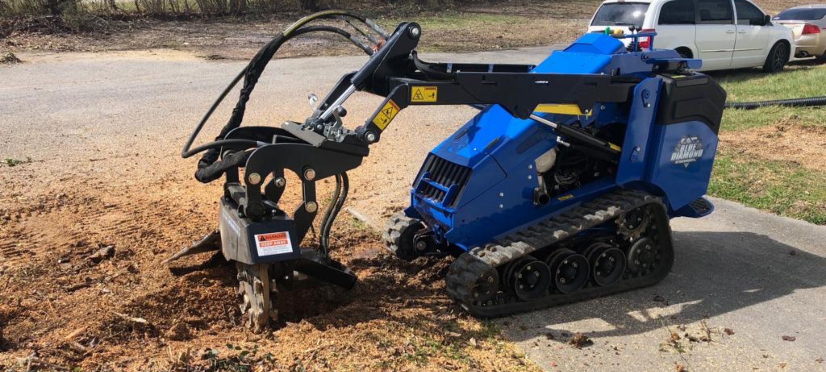 Stump grinder on a mini skid steer from blue diamond in action