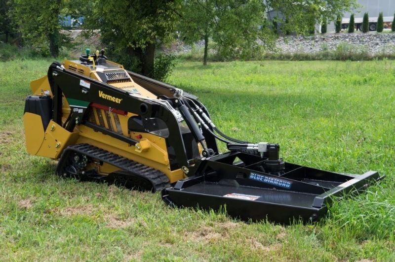 Vermeer mini skid steer with the closed front brush cutter attachment from Blue Diamond clearing the grass