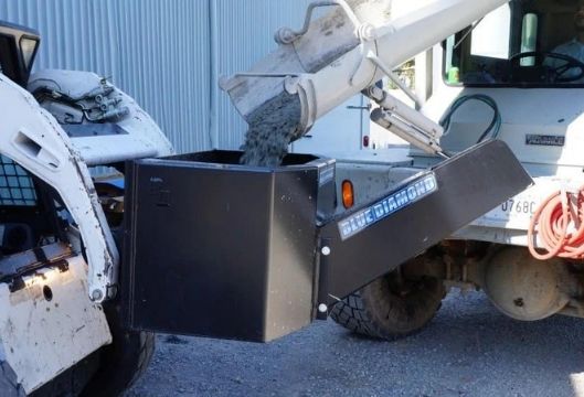 Pouring concrete in the concrete attachment from Blue Diamond on a bobcat skid steer