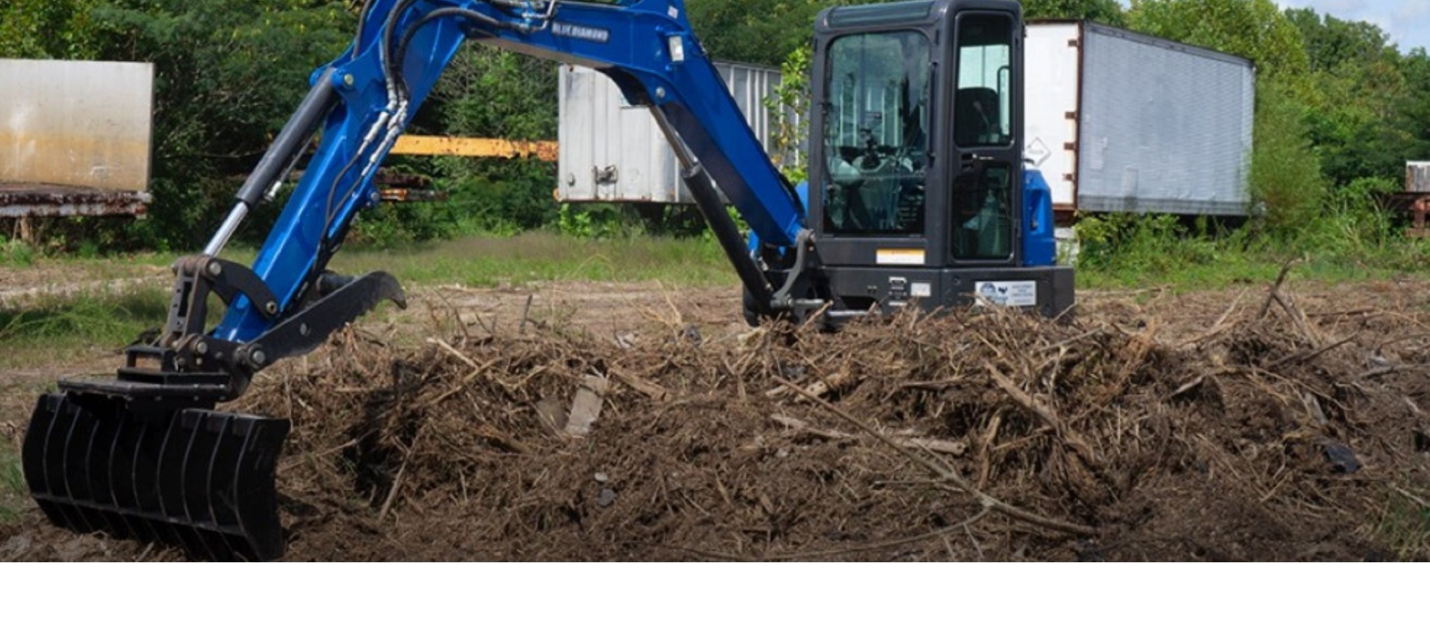 Excavator removing dirt with the Blue Diamond root rake attachment. 