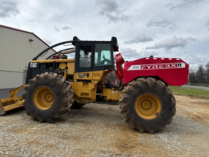 Large CAT machine equipped with a red FYREBX S10 attachment parked on gravel under a cloudy sky