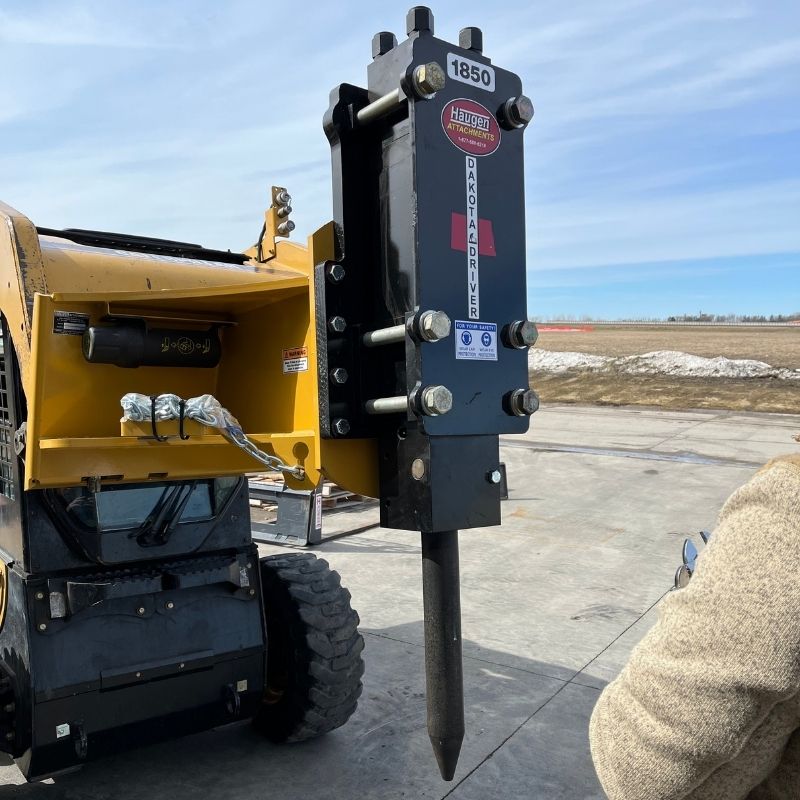 Skid steer ready to drill hole with the Dakota Post Driver attachment from Haugen. 