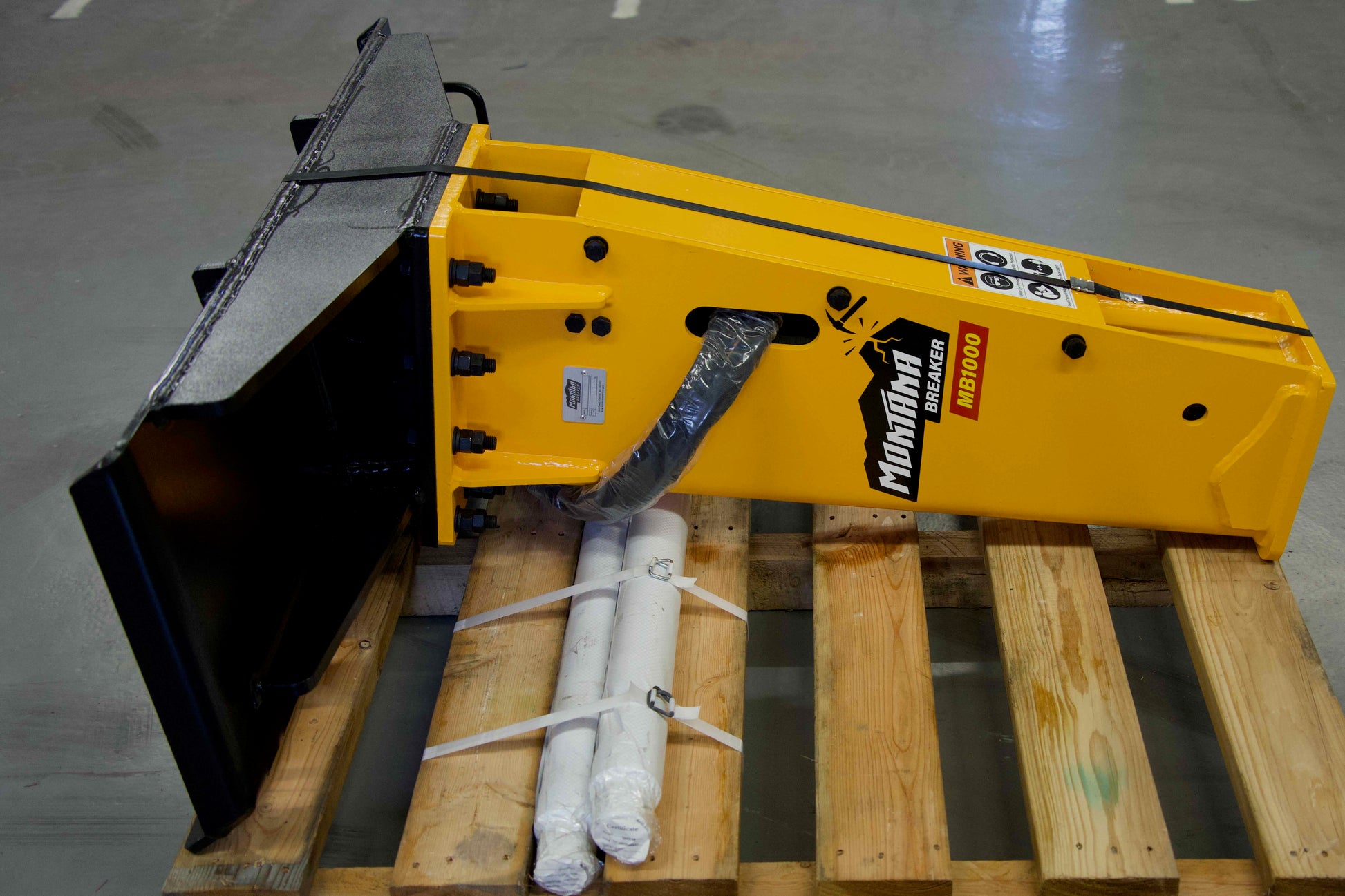 Montana MB1000 hydraulic breaker attachment displayed on a pallet with hoses and accessories