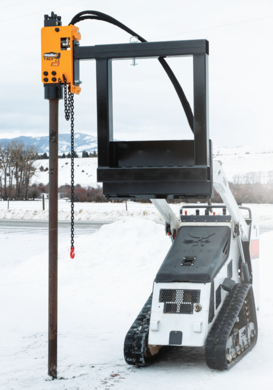 Montana T-Rex 350E post driver mounted on a Bobcat mini skid steer driving a fence post in snow