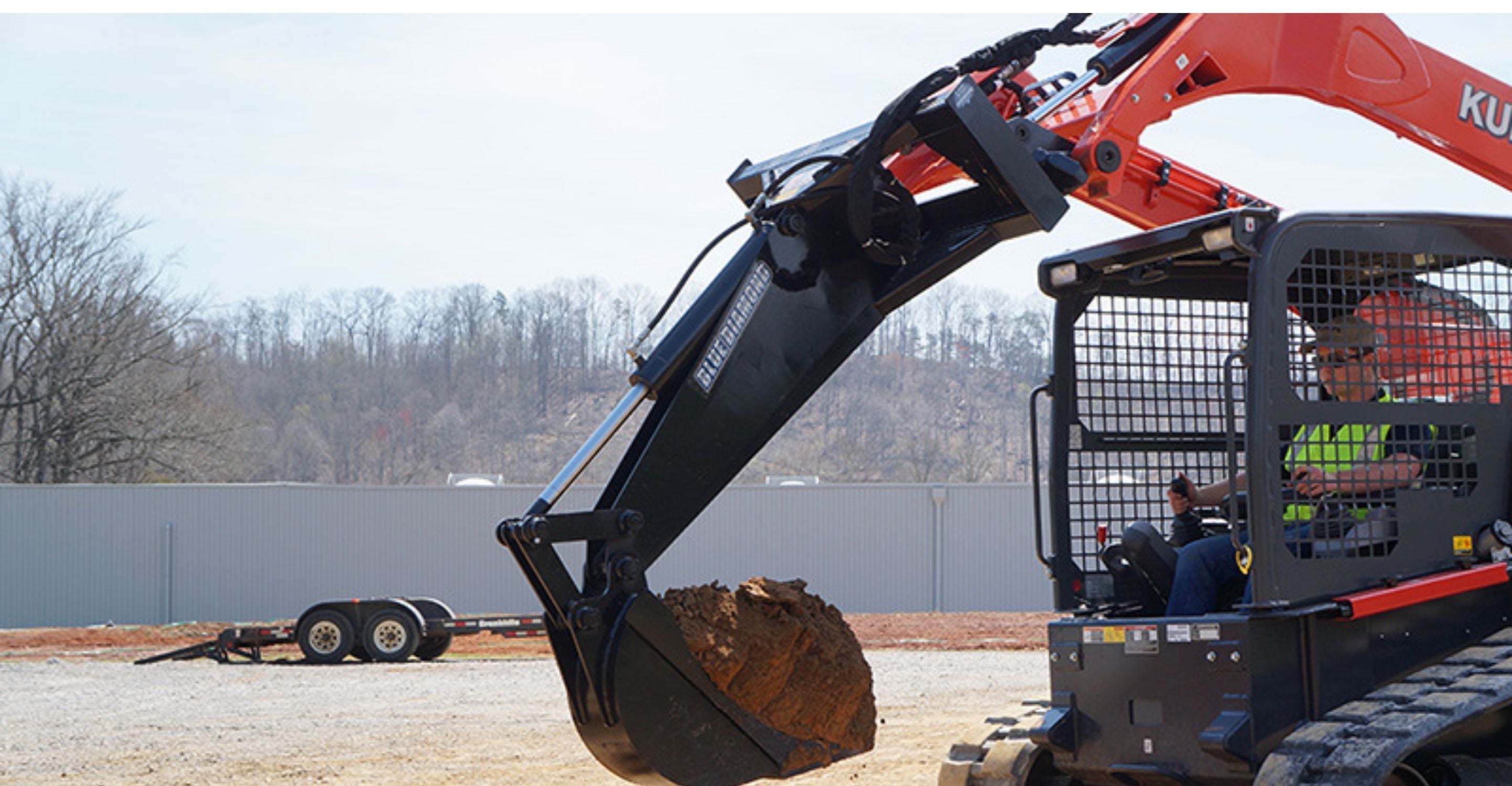 Backhoe attachment on a Kubota skid steer with dirt