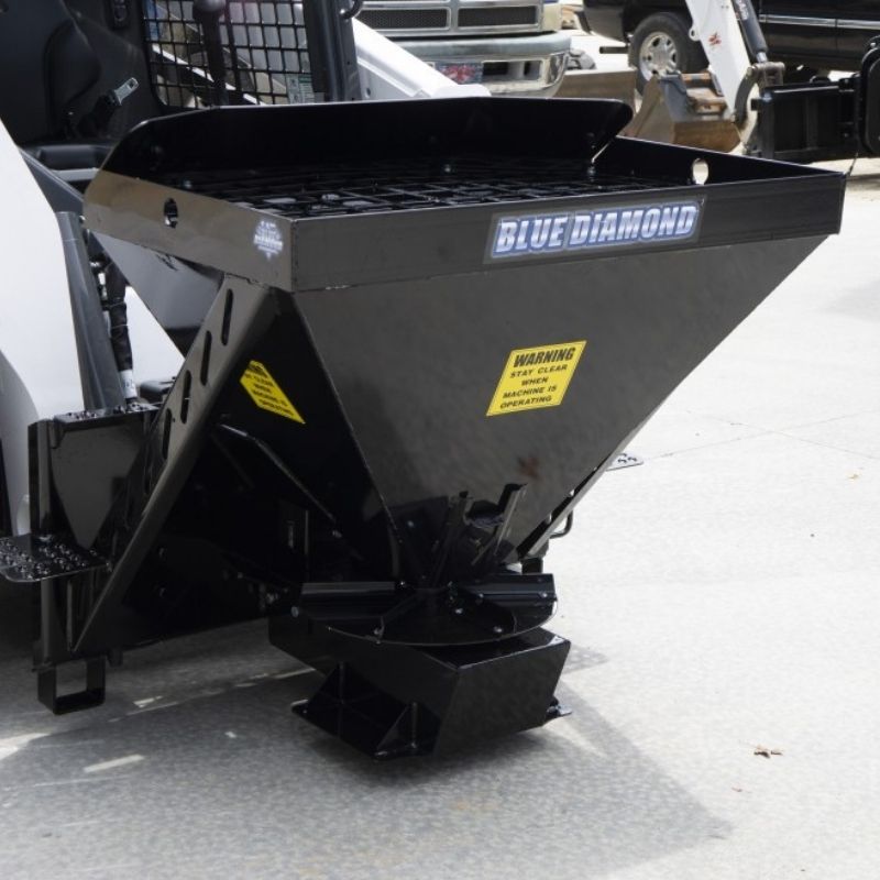 Blue diamond material spreader attachment on the ground for skid steers