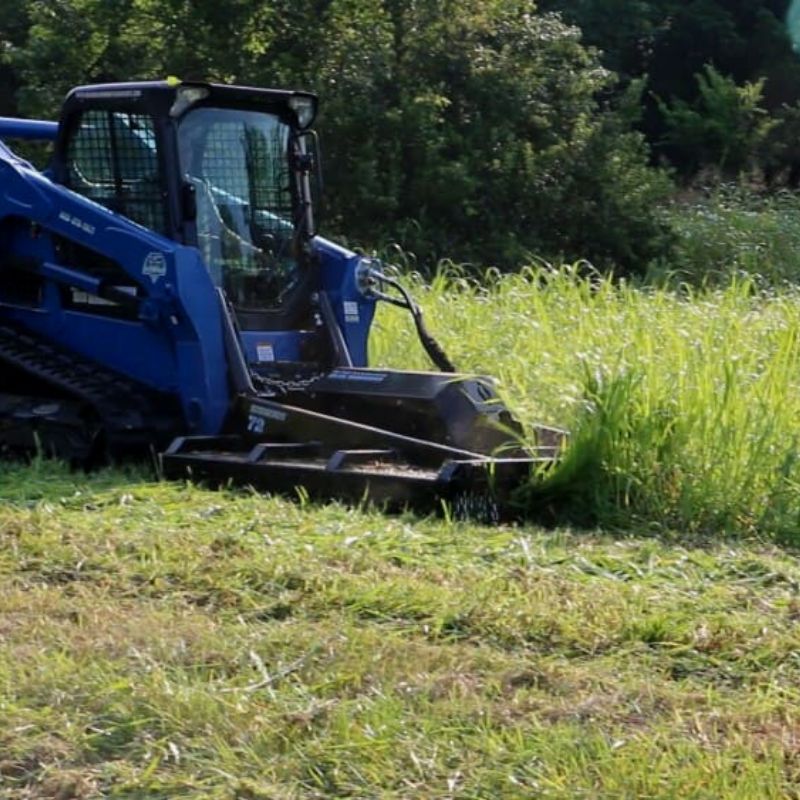 skid steer in action with the blue diamond brush cutter attachment