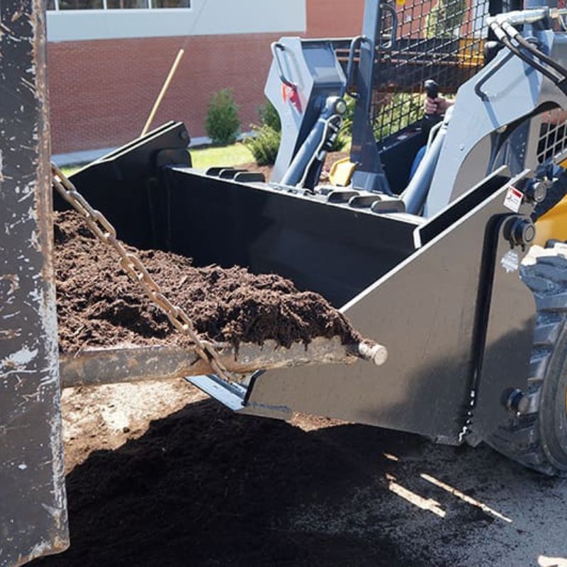 4 in 1 bucket on a John Deere skid steer loading dirt