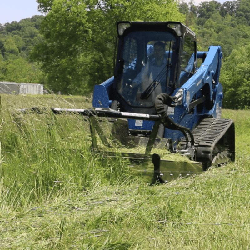 skid steer cutting grass with a blue diamond brush cutter