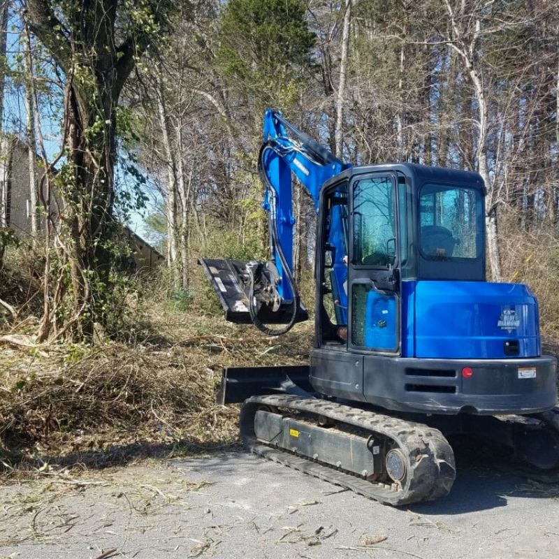 mini excavator in action with blue diamond brush cutter