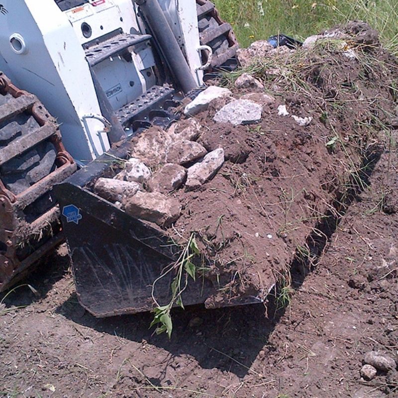 skid steer with blue diamond bucket attachment with dirt