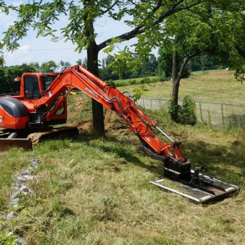 cutting grasses with the mini excavator using the blue diamond brush cutter attachment