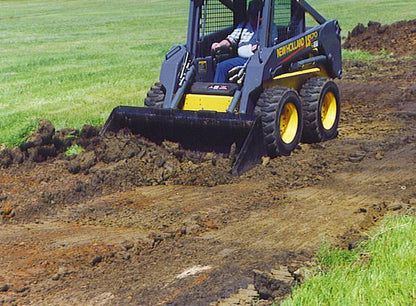 new holland skid steer picking up dirt with the heavy duty fertilizer and grain bucket attachment by star industries