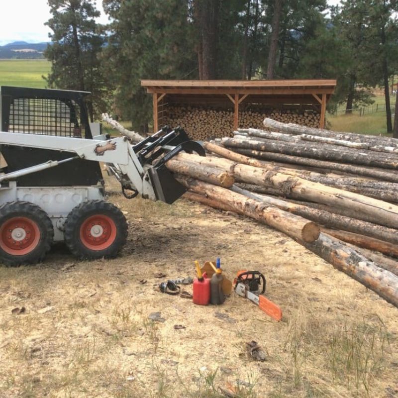 Small skid steer using blue diamonds light duty root grapple to move logs