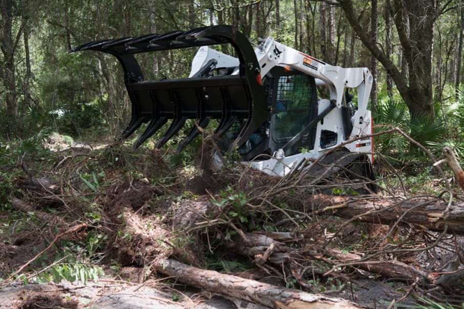 bobcat skid steer in action with the severe duty rake grapple from mclaren industries
